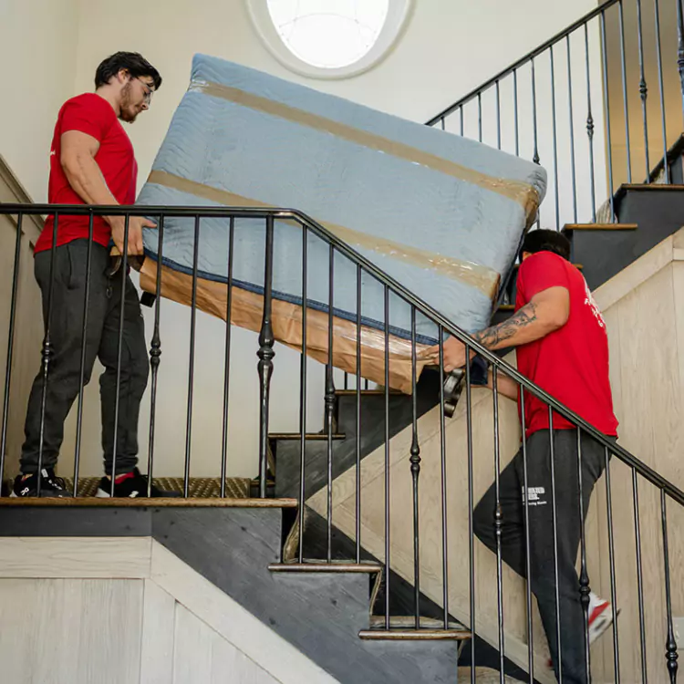 A Motivated Movers professional securely carries furniature up the stairs, showcasing expert moving and handling skills.