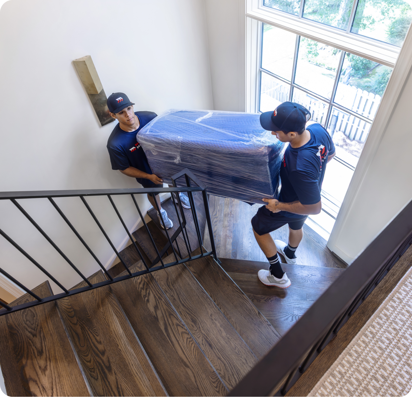 Motivated Movers moving sofa down stairs.